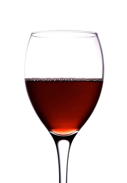 a glass of wine is sitting in front of the white backdrop