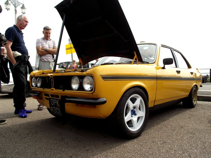 a yellow car with it's hood open at an event