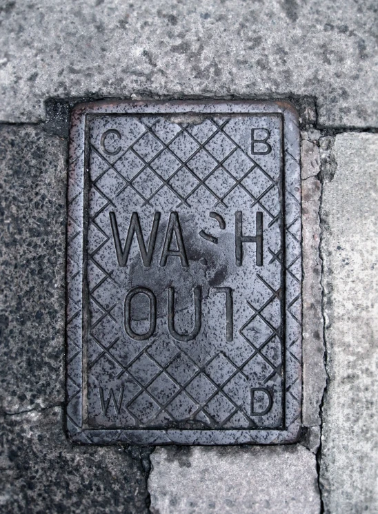a manhole cover that says wash out on the sidewalk