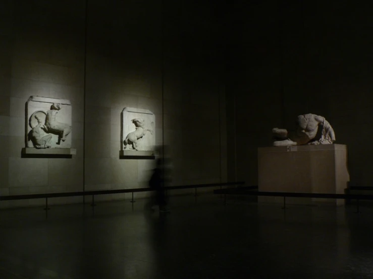 a man stands in the dark next to some statues