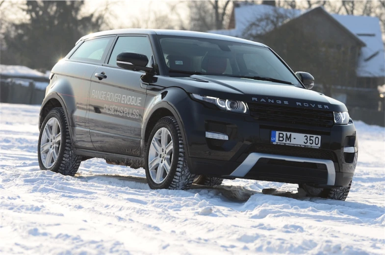 a land rover on snow in front of houses