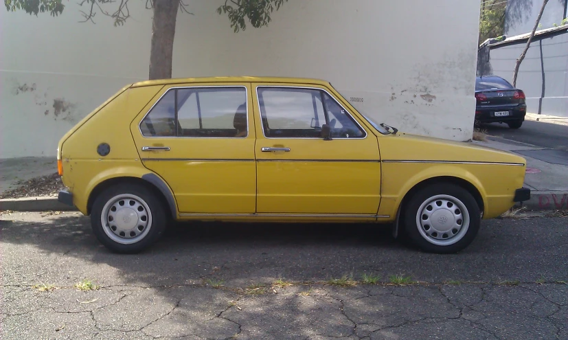 the yellow car is parked on the pavement