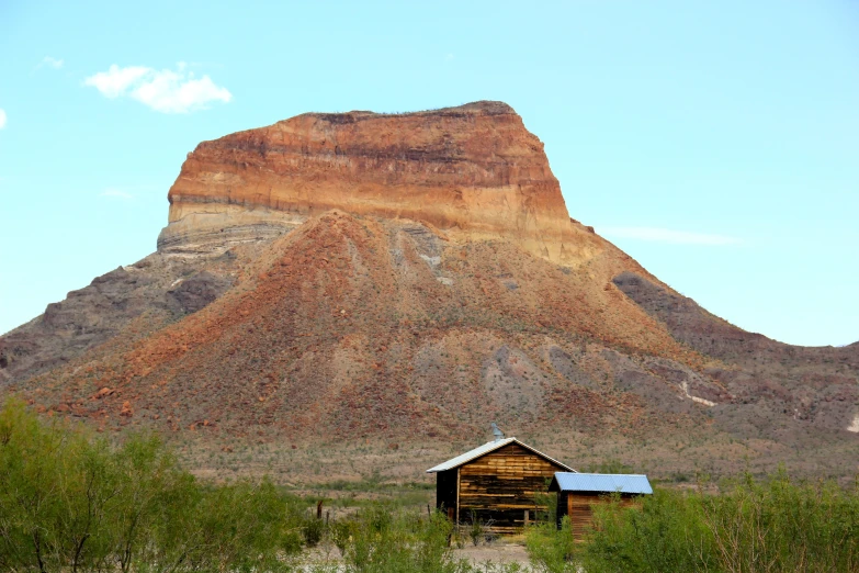 an old cabin in front of the huge mountains