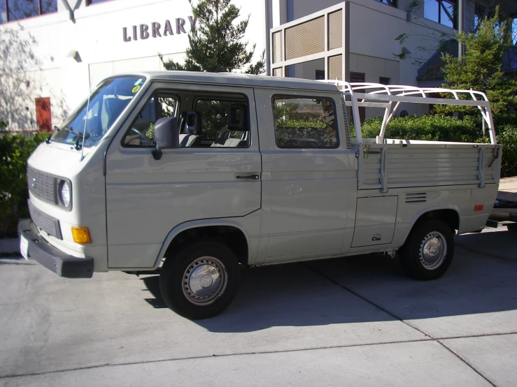 a small white utility van parked outside of a liry