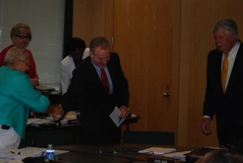 a group of men standing around a table in front of people