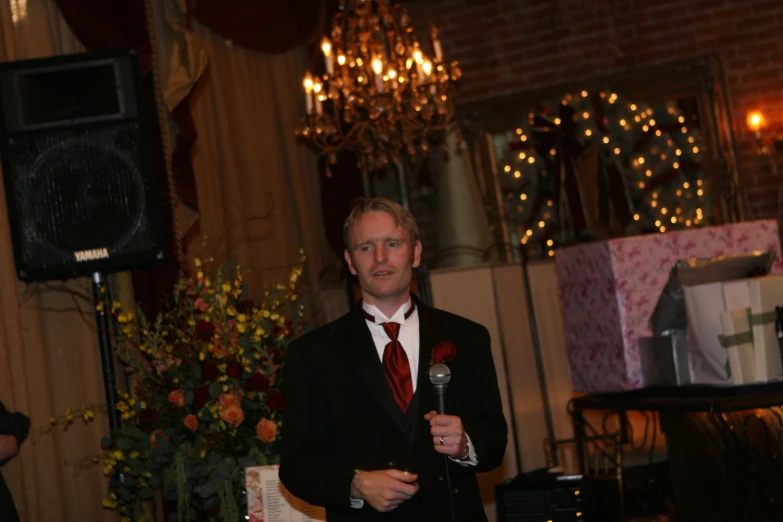 a man in black suit with red tie holding a microphone