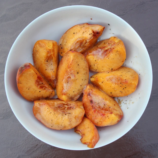 a white bowl of fried potatoes with a gray surface