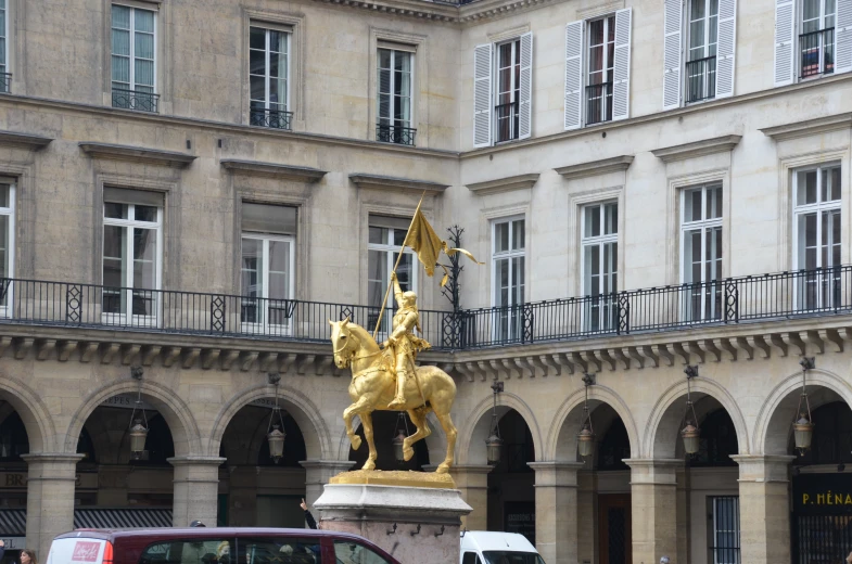 an old city courtyard with statues and cars parked near it