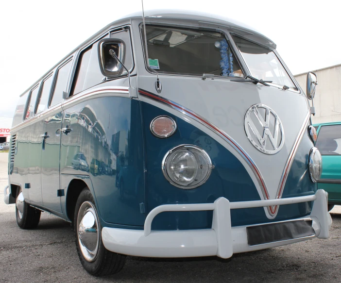 a blue and white volkswagen bus is parked in a lot