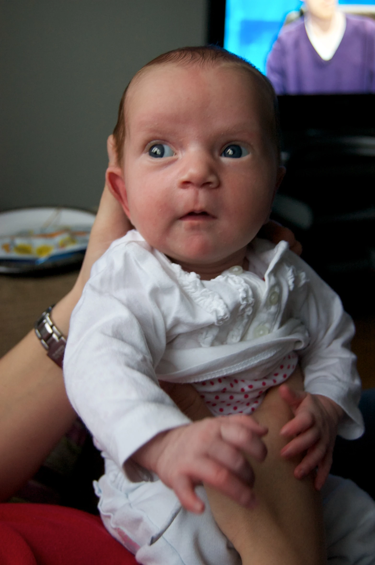 a little  being held by a woman in a white shirt