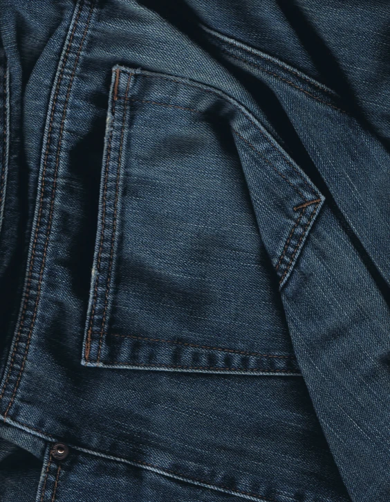a pile of blue jeans with a black stripe on them