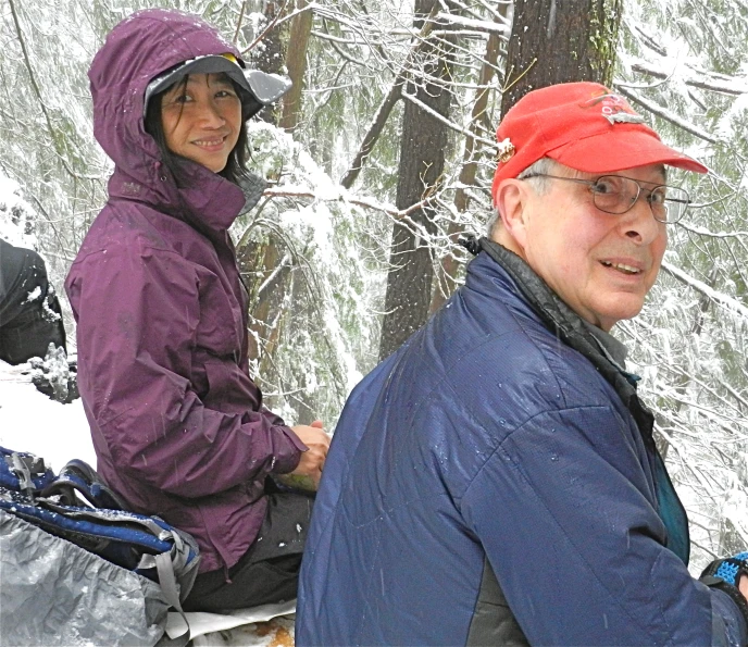 two people wearing jackets and hats are standing in the snow