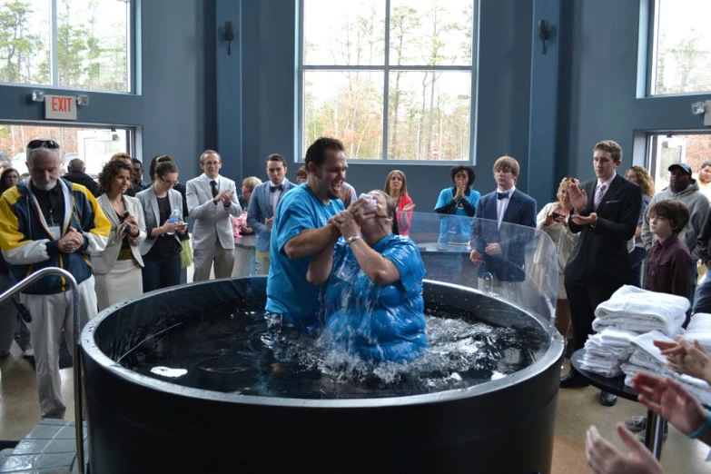 a man in blue shirt next to a  tub filled with water