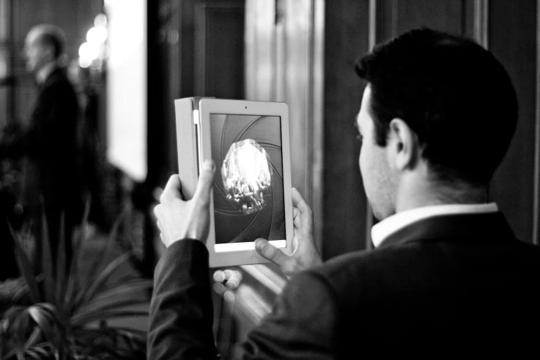 black and white pograph of a man holding up an old portrait