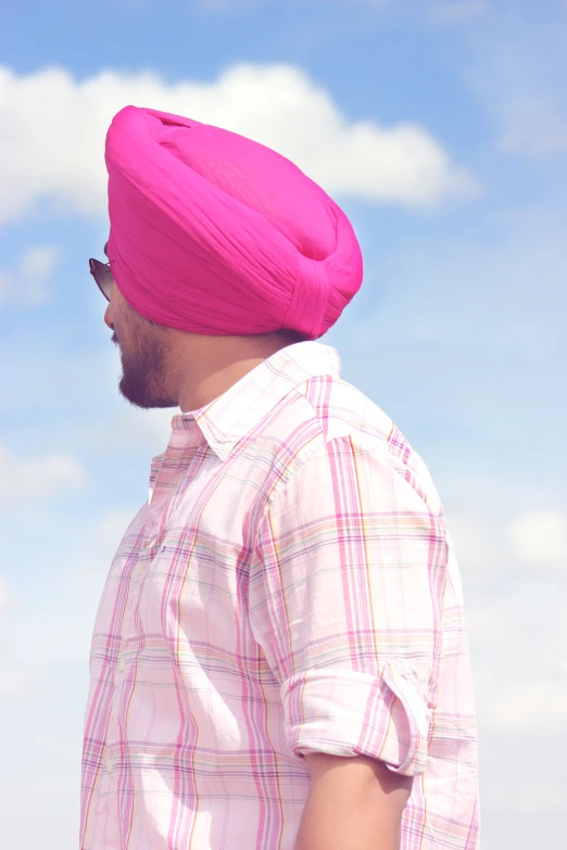 man in pink turban gazing down at sky