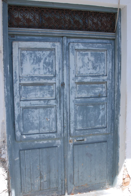 two old and worn blue doors with wrought iron bars on each side
