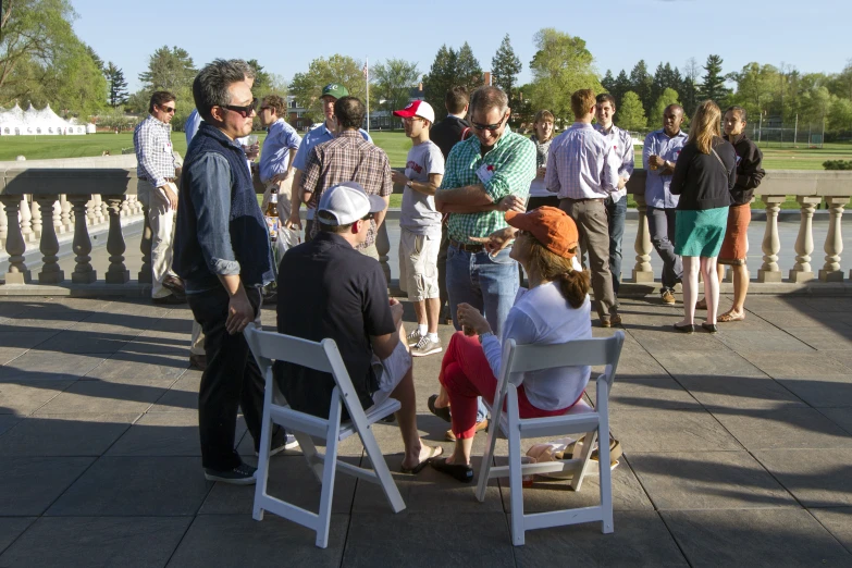 people are gathered outside having a drink on their knees