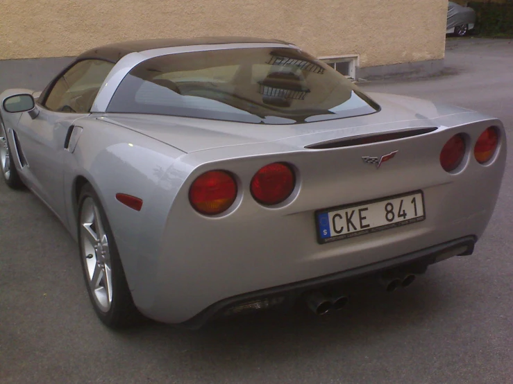 a grey sports car is parked next to the building