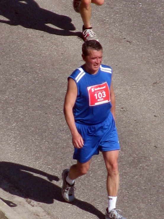 a man in a marathon uniform runs on the street