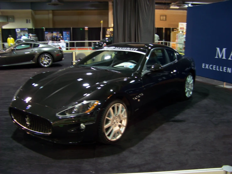 a dark colored masera is on display in front of other cars