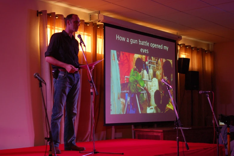 a man standing in front of a red carpeted stage while talking to someone