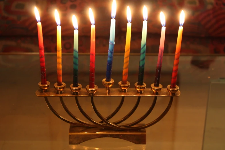many candles lit with colored lights on an old metal stand