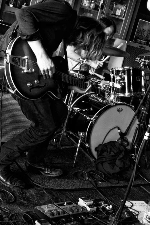 two people are playing drums in front of a guitar