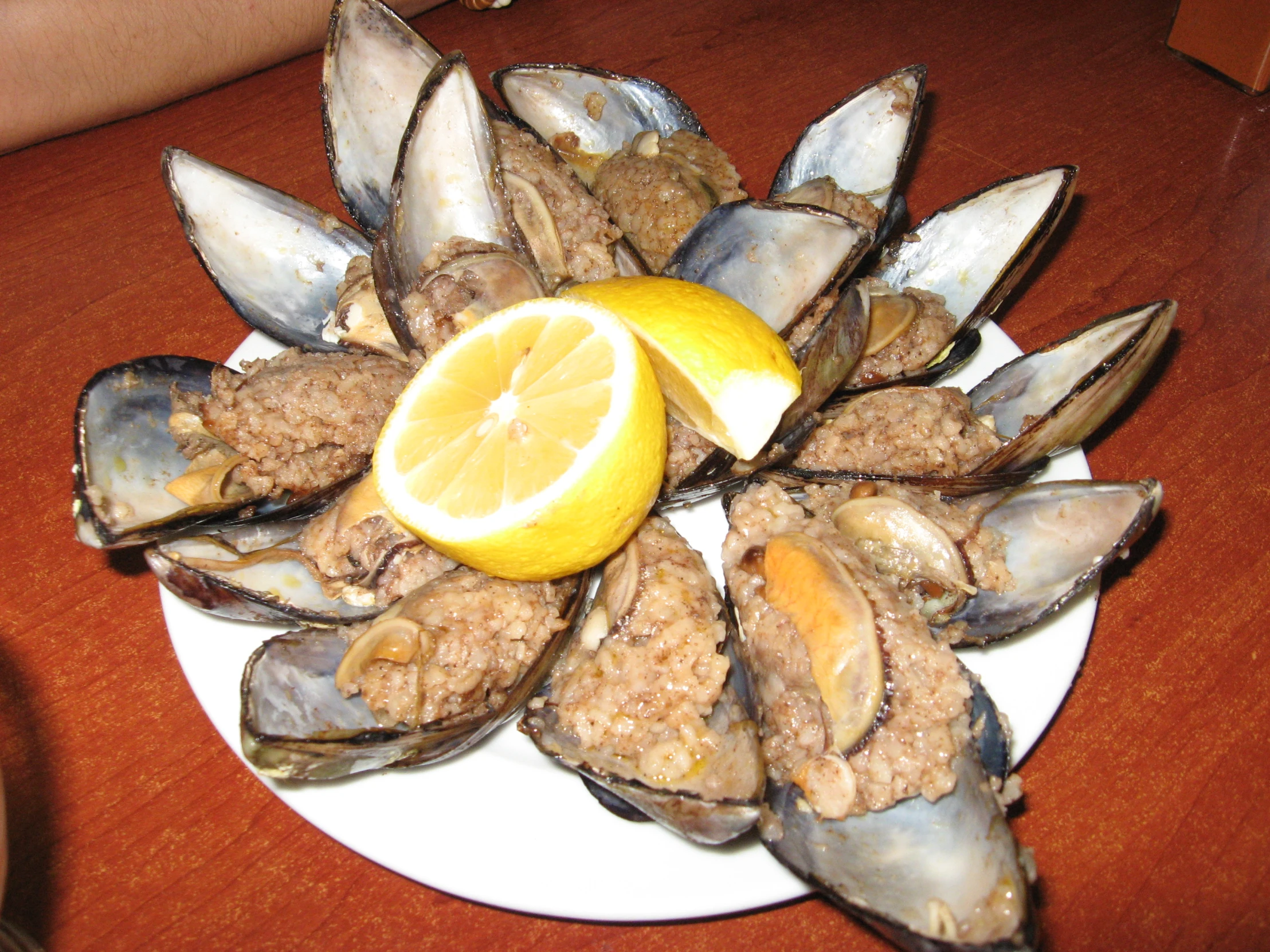 a plate of cooked mussels and a lemon slice