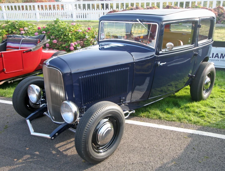 an old fashion car parked next to a car with a fence