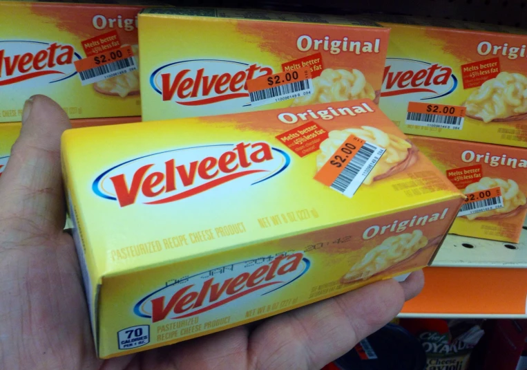 a person holding out a box of velveeta