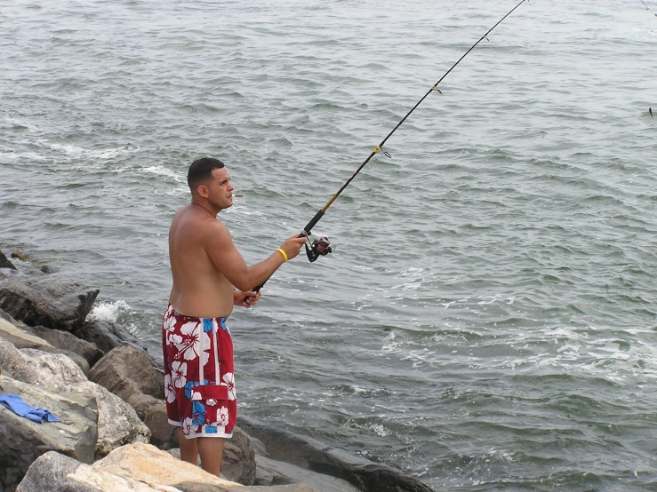 a man with red trunks and his surfboard is fishing in the ocean