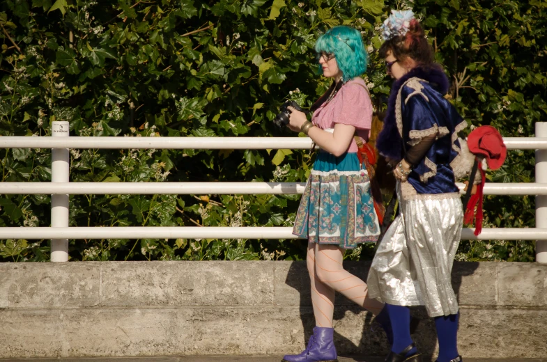 two women wearing costumes standing next to a fence