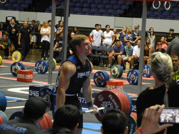 a man in a crossfit competition squats on one leg