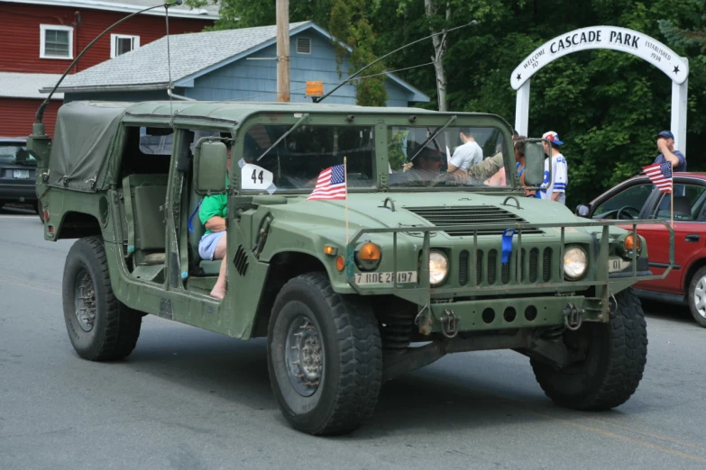 two people are driving a large truck with flags on the windshield