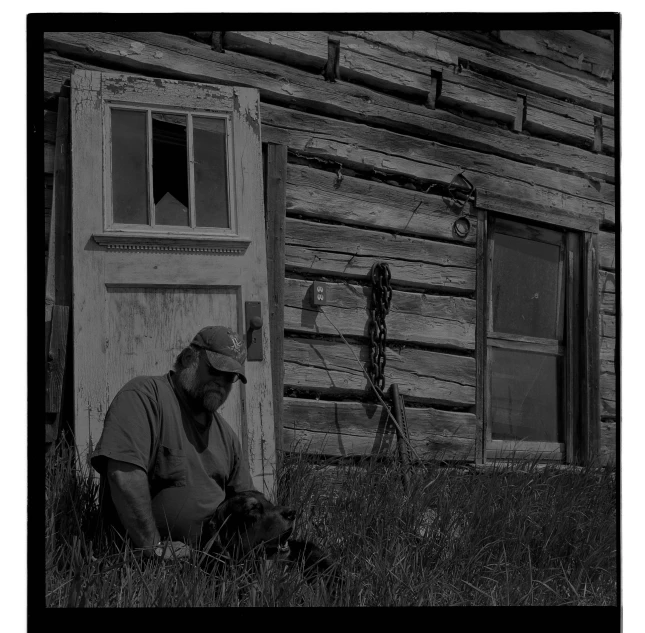 a man kneeling in the grass next to a door