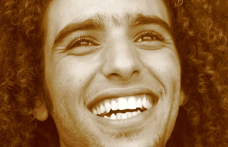 a man with a tie and curly hair smiling