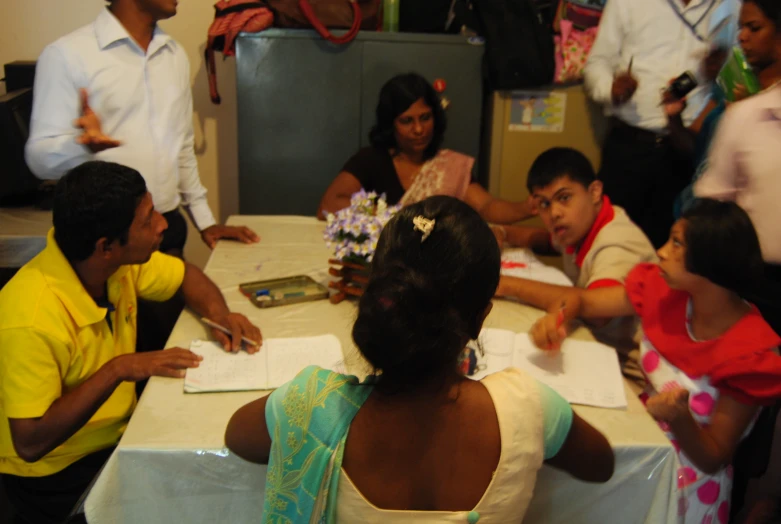 children are sitting at a table with white cloths