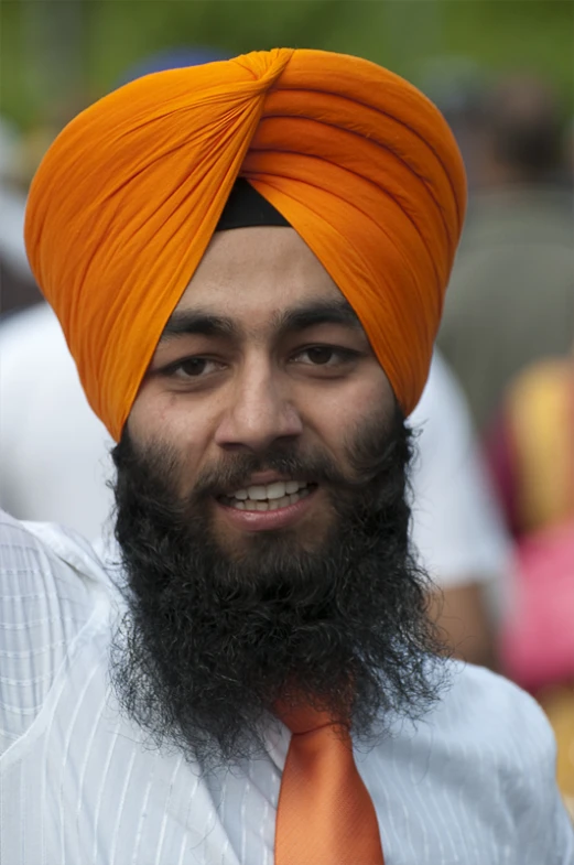 the man is wearing an orange turban over his shirt