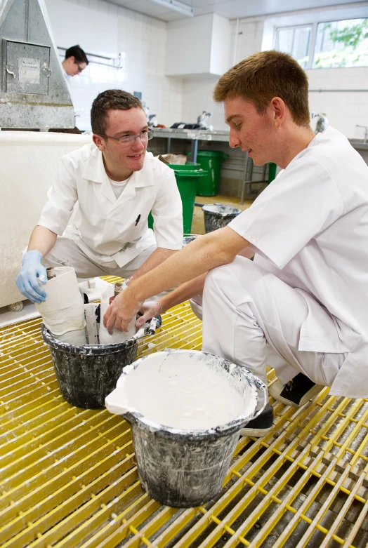 two chefs in white work together in a kitchen