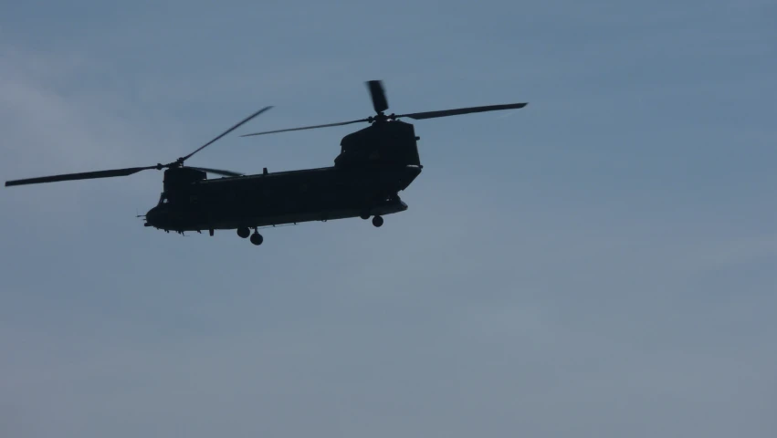 a military helicopter flying against the blue sky