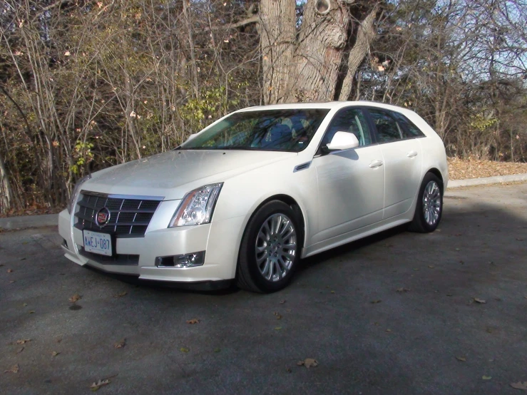 a white cadillac parked in front of some trees