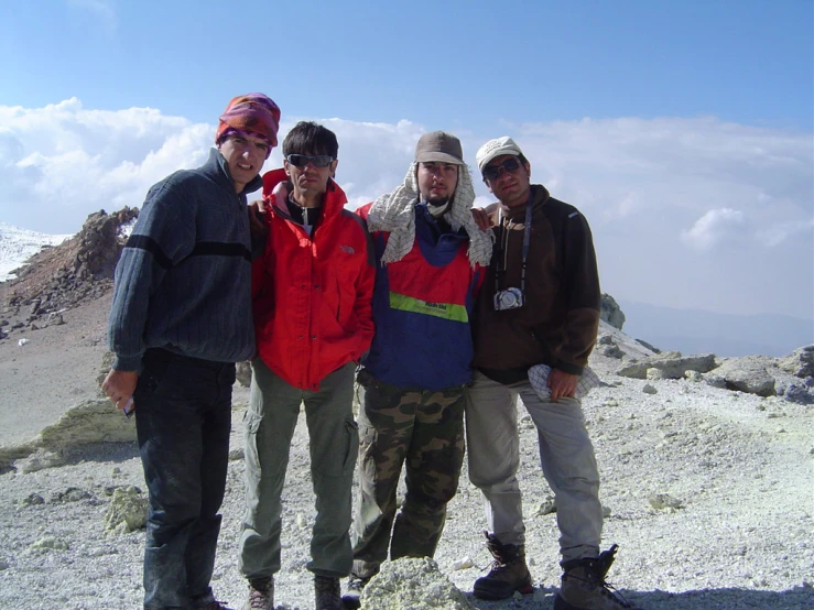 four young men stand on the side of a mountain