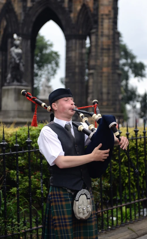 man playing bagpipe in front of a castle