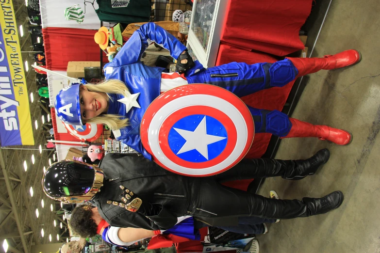 a woman in costume poses with a man with a shield