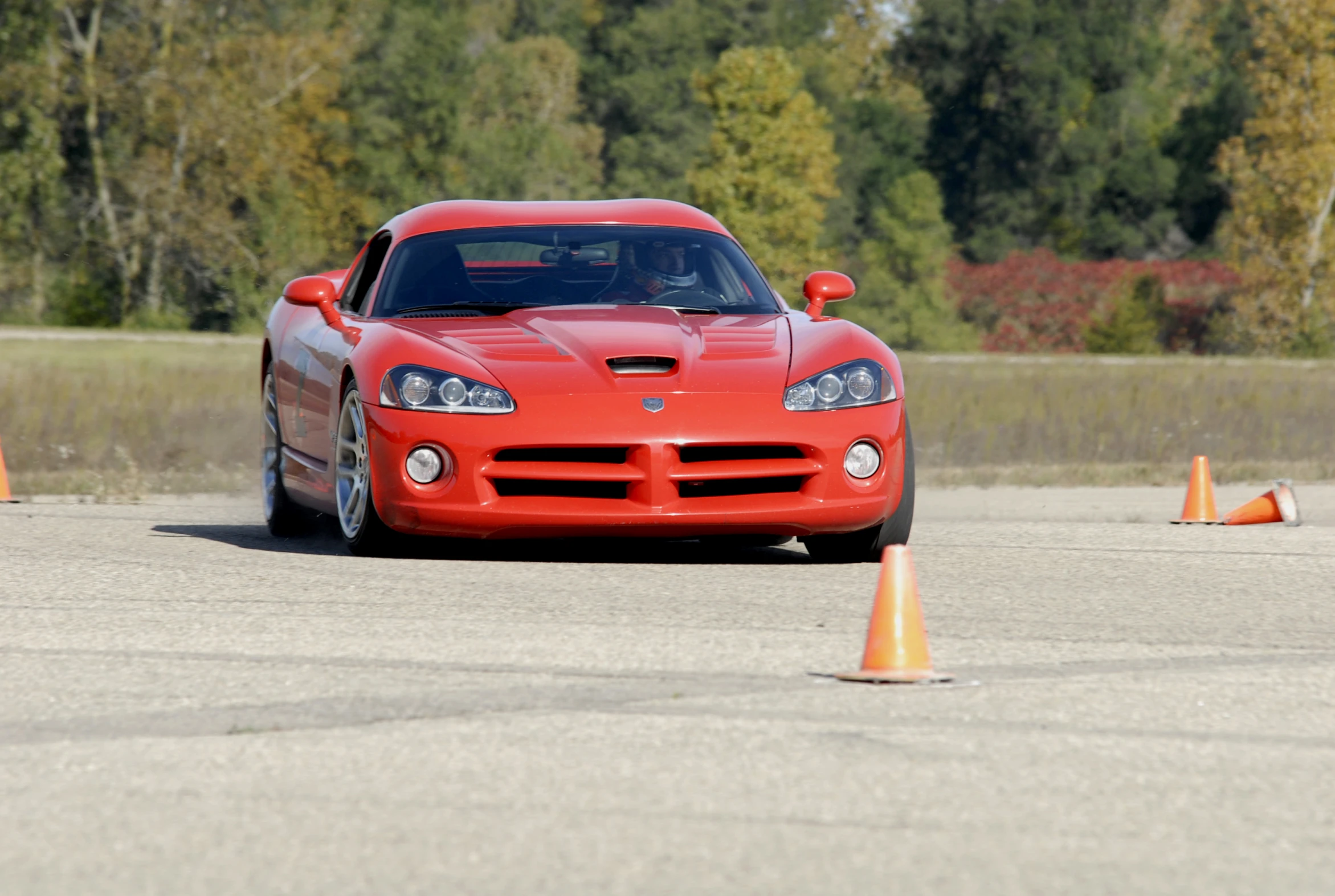 a red car driving past orange cones on the road