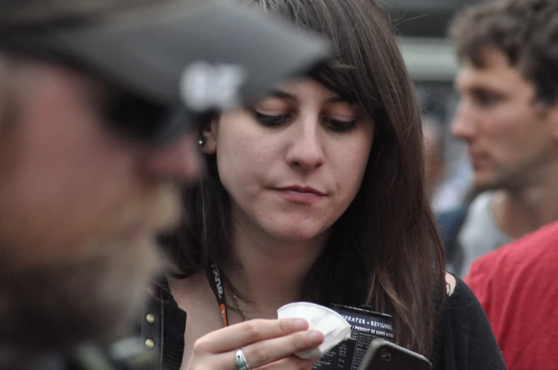 a woman is looking at her phone while standing near a man