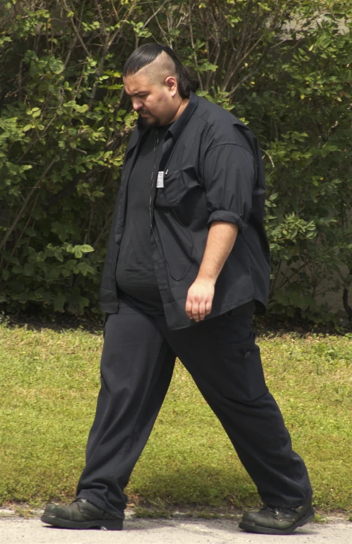 a large man is walking through a park
