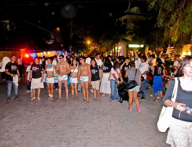 large group of people standing in a street at night