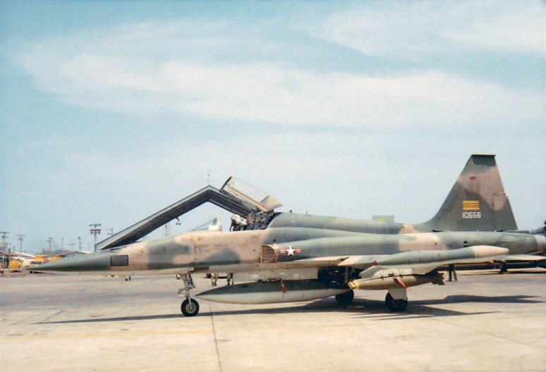 a fighter jet is parked with an open door