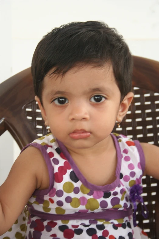 little girl sitting on a chair with polka dot print dress